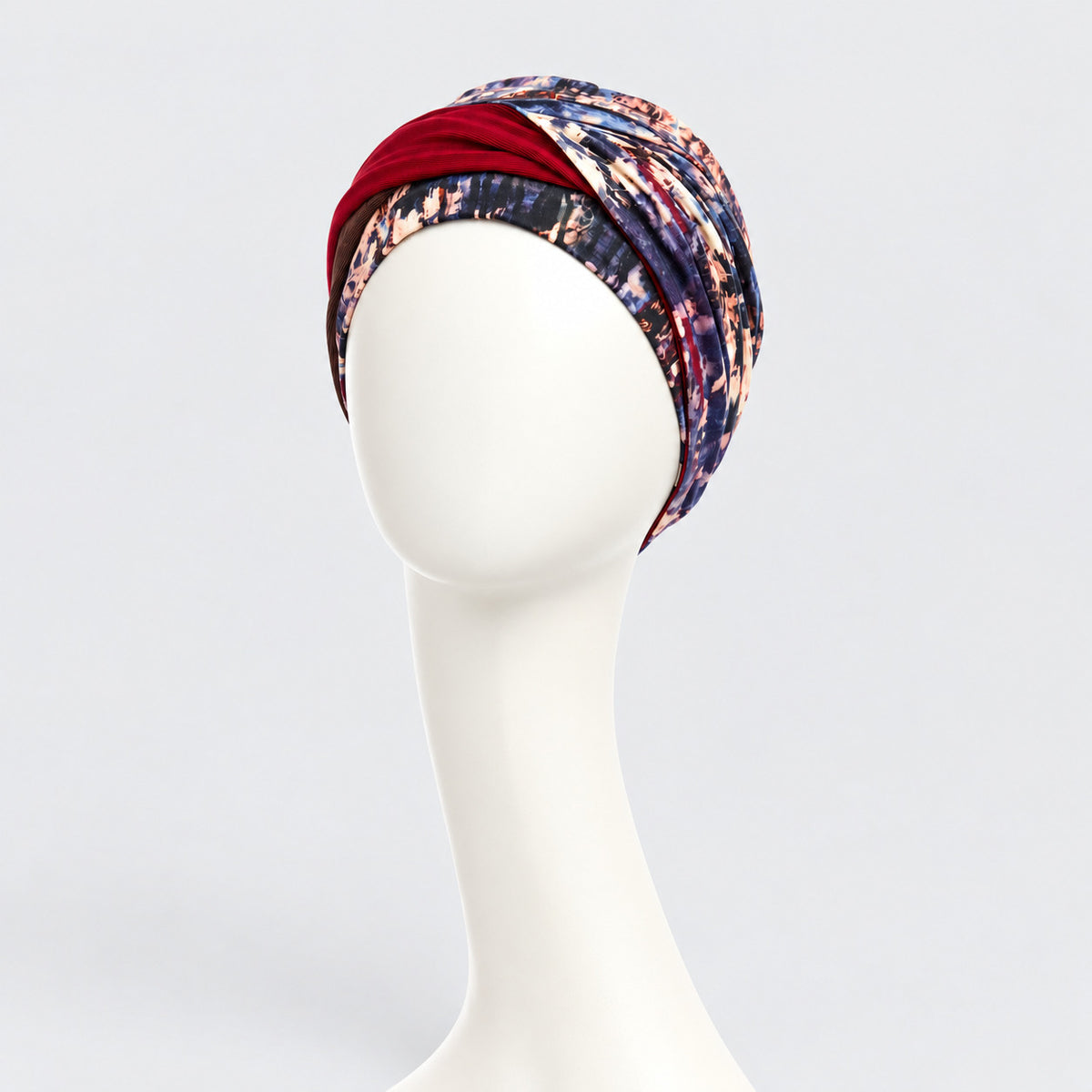 Turbante oncológico Shakti Tie Dye Dusk de Christine Headwear, vista frontal con estampado multicolor y banda burdeos.